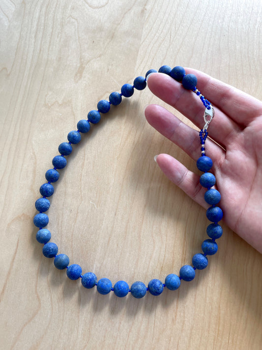 A. Necklace of matte blue Lapis with a sterling silver lobster claw clasp